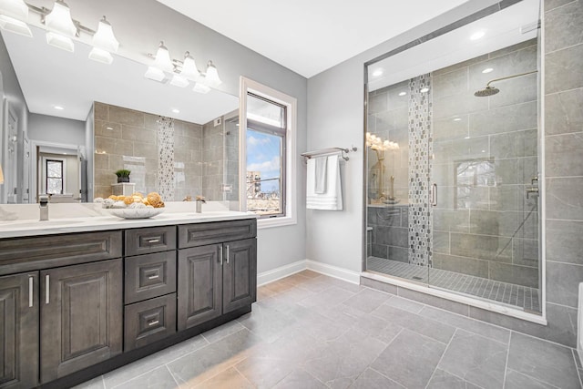 bathroom with a shower stall, double vanity, baseboards, and a sink