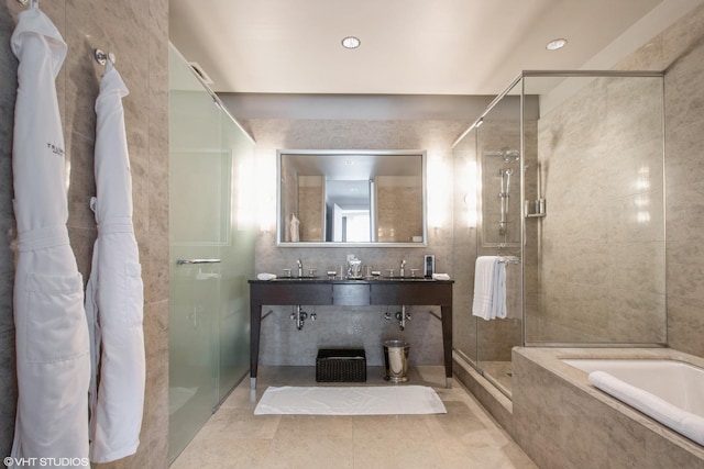 bathroom with tile patterned floors, double vanity, a bath, and a shower stall