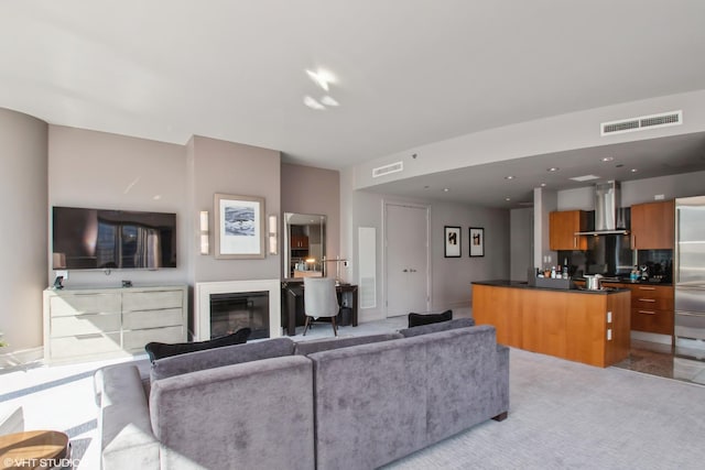 living area featuring a glass covered fireplace, recessed lighting, light colored carpet, and visible vents