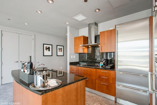 kitchen with ventilation hood, stainless steel built in refrigerator, brown cabinets, black electric cooktop, and a sink