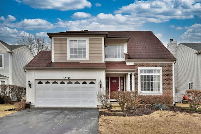 traditional-style home featuring driveway, brick siding, and roof with shingles