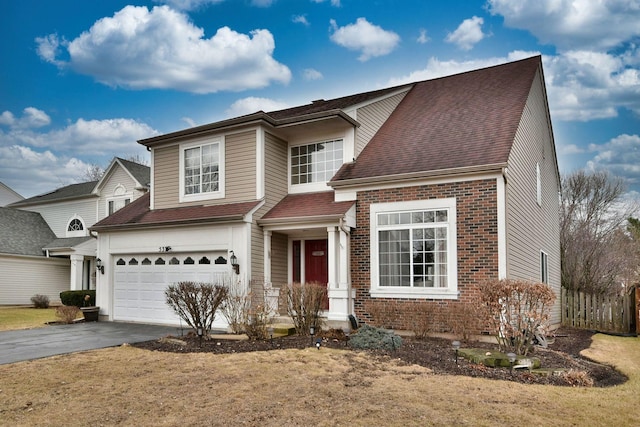 traditional home with an attached garage, roof with shingles, aphalt driveway, and brick siding