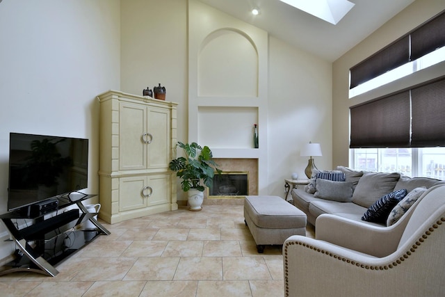 living area with high vaulted ceiling, a skylight, light tile patterned floors, and a premium fireplace