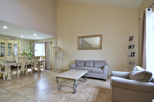 living room featuring light tile patterned floors, a towering ceiling, and recessed lighting