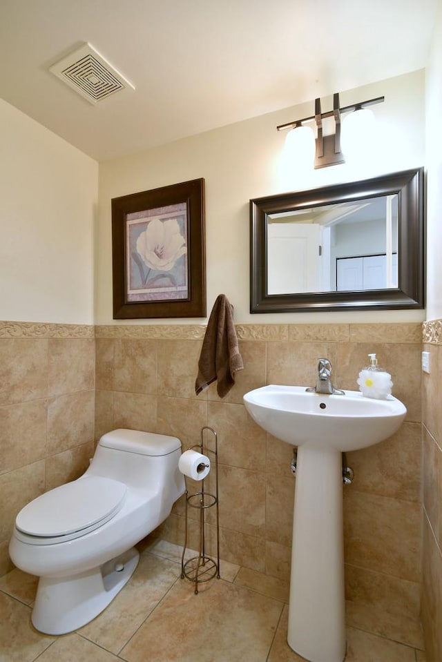 bathroom featuring visible vents, wainscoting, toilet, tile patterned flooring, and tile walls