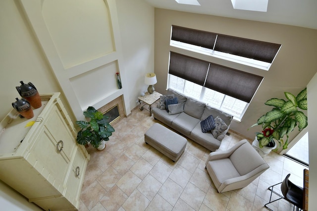 living room with a skylight, light tile patterned floors, and a glass covered fireplace