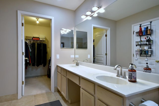 full bathroom with double vanity, a spacious closet, tile patterned flooring, and a sink