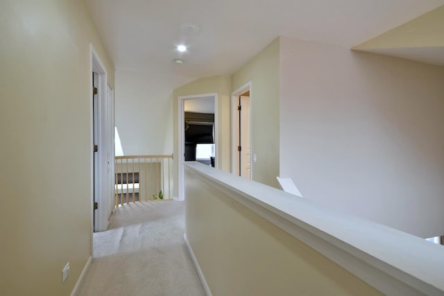 corridor featuring baseboards, light colored carpet, and an upstairs landing