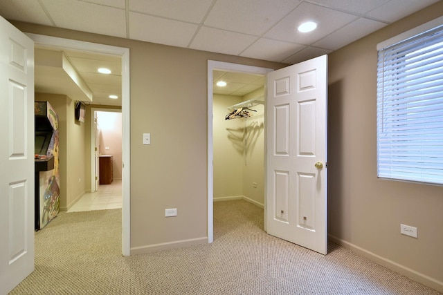 unfurnished bedroom with a walk in closet, a paneled ceiling, recessed lighting, light carpet, and baseboards