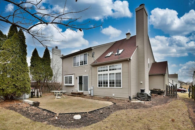 rear view of property with entry steps, a patio area, fence, and a chimney