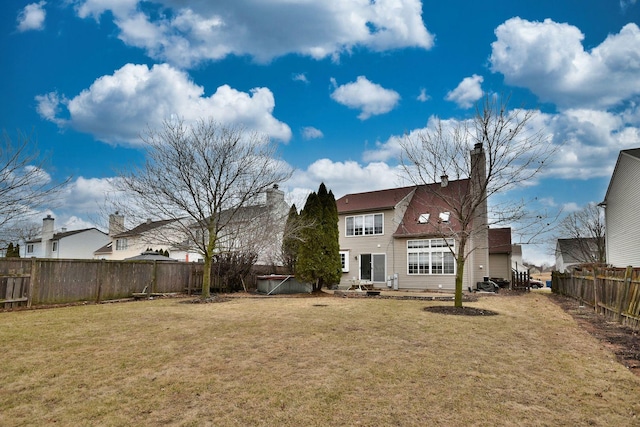 rear view of property featuring a lawn and a fenced backyard