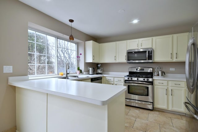 kitchen with a peninsula, stainless steel appliances, light countertops, white cabinetry, and a sink