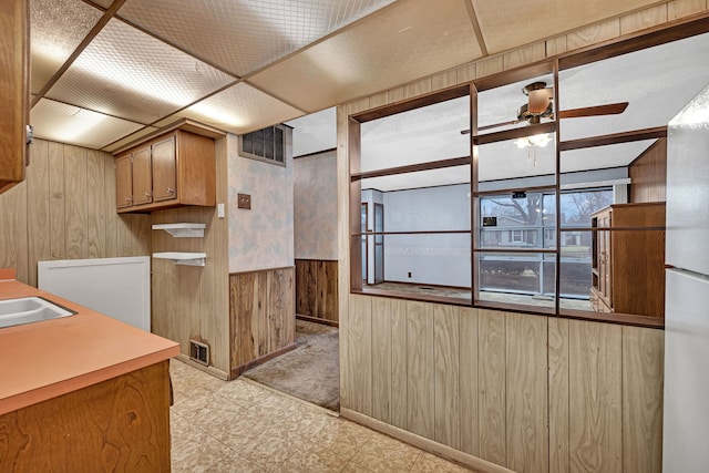 kitchen with light floors, visible vents, a ceiling fan, wainscoting, and wooden walls