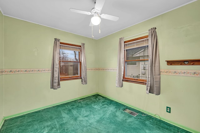 empty room with carpet, visible vents, and a ceiling fan