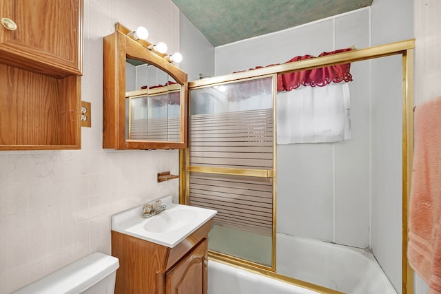 bathroom with toilet, vanity, tile walls, combined bath / shower with glass door, and backsplash