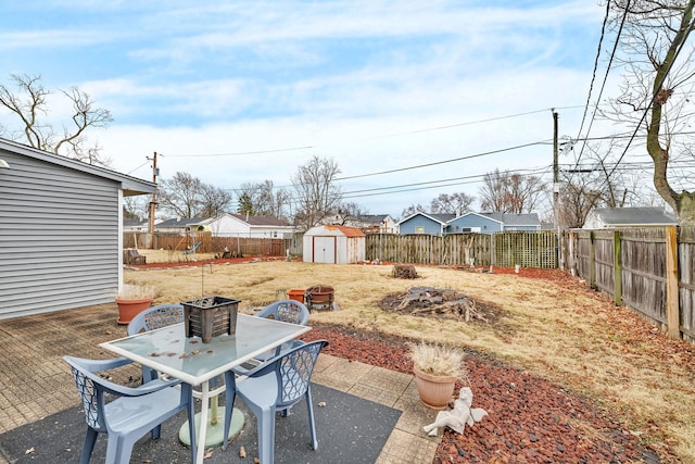 view of yard featuring outdoor dining space, a fenced backyard, an outdoor structure, a shed, and a patio area