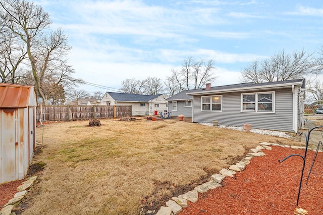 back of house featuring a fire pit, a lawn, a chimney, and fence