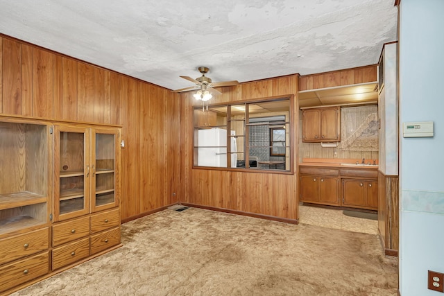 kitchen featuring ceiling fan, wood walls, a sink, carpet flooring, and freestanding refrigerator