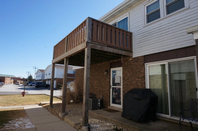 exterior space with a deck, brick siding, and central AC unit