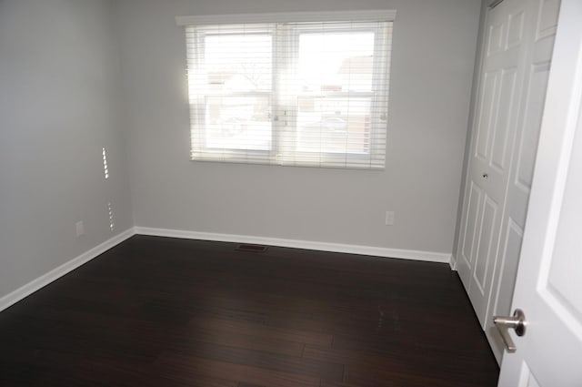 empty room featuring dark wood-style floors, plenty of natural light, and baseboards