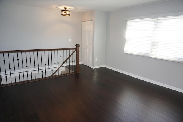 spare room with dark wood-style flooring, visible vents, and baseboards