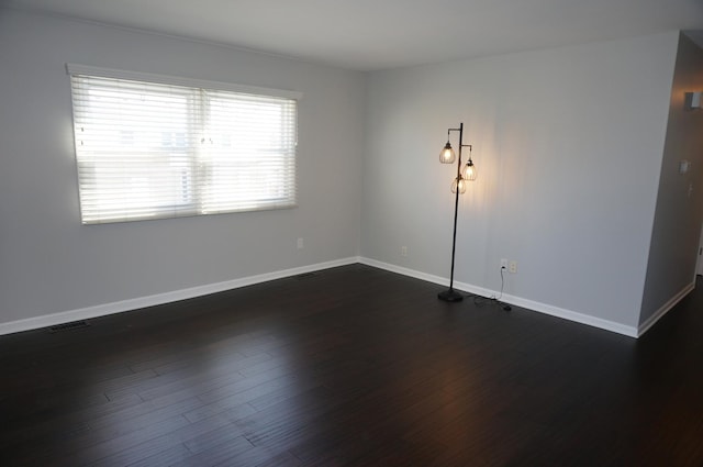 empty room featuring baseboards, visible vents, and dark wood-type flooring