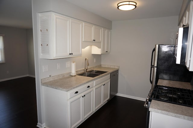 kitchen with white cabinets, appliances with stainless steel finishes, dark wood-type flooring, light countertops, and a sink