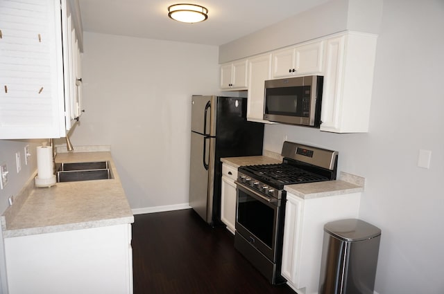 kitchen with baseboards, dark wood-style floors, appliances with stainless steel finishes, light countertops, and white cabinetry