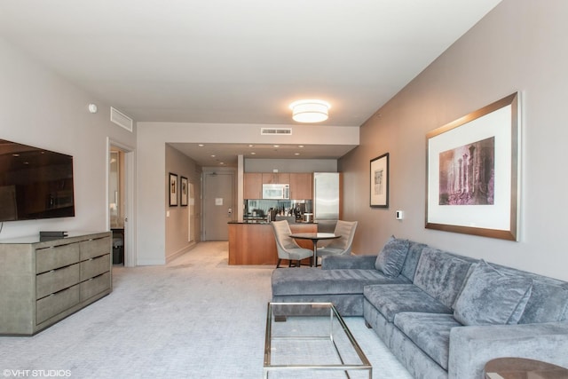 living room with visible vents, baseboards, and light colored carpet