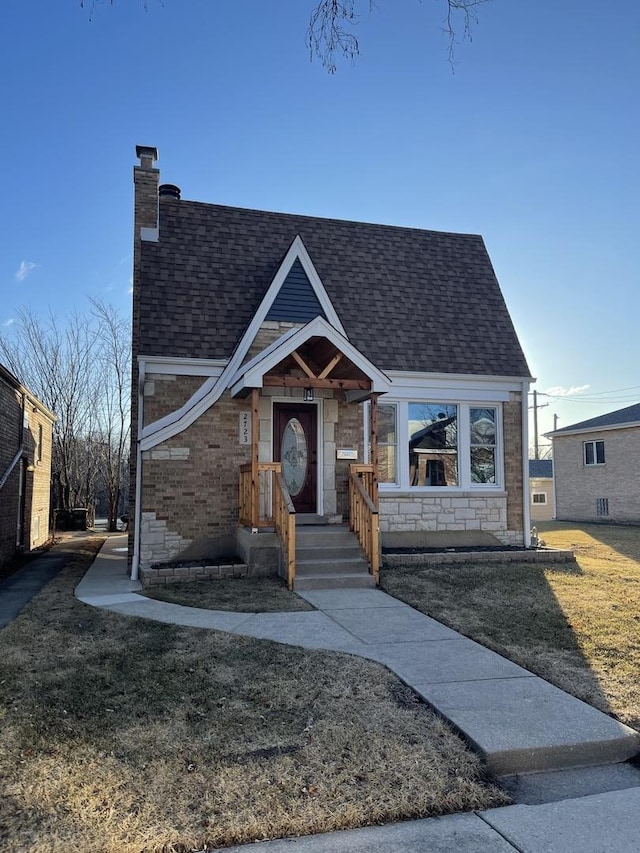 view of front of property featuring stone siding, roof with shingles, and a chimney