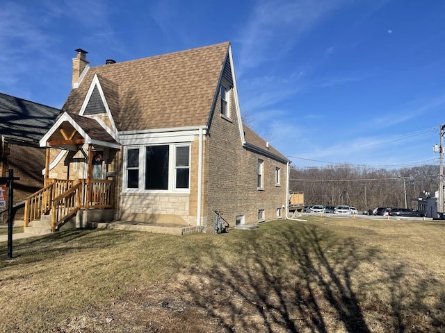 view of property exterior with brick siding, a shingled roof, a yard, stone siding, and a chimney