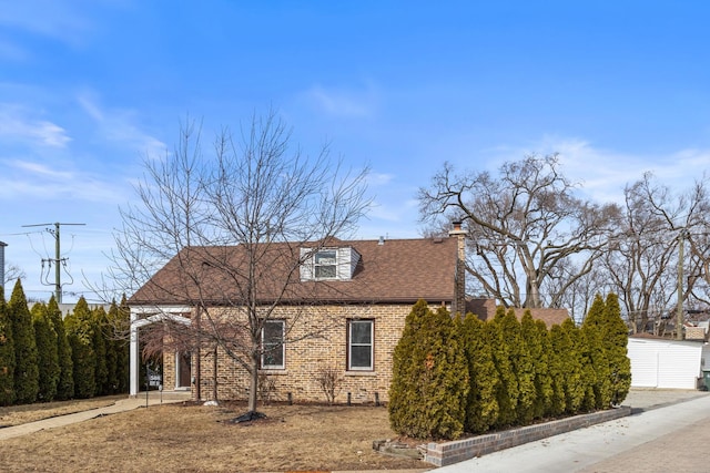 view of front of house featuring roof with shingles, a chimney, and brick siding