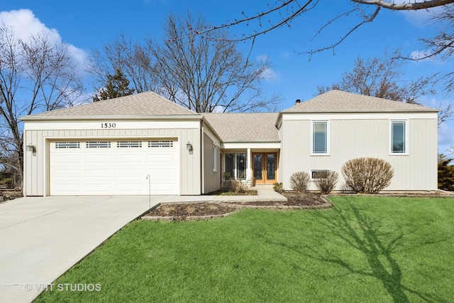 view of front facade with french doors, driveway, an attached garage, and a front yard