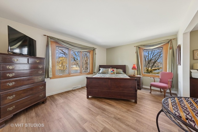 bedroom featuring visible vents, light wood-type flooring, and baseboards