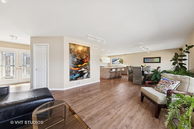 living room featuring rail lighting, wood finished floors, visible vents, and french doors