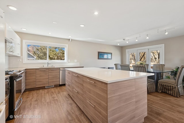 kitchen featuring light wood-style floors, a kitchen island, modern cabinets, and appliances with stainless steel finishes