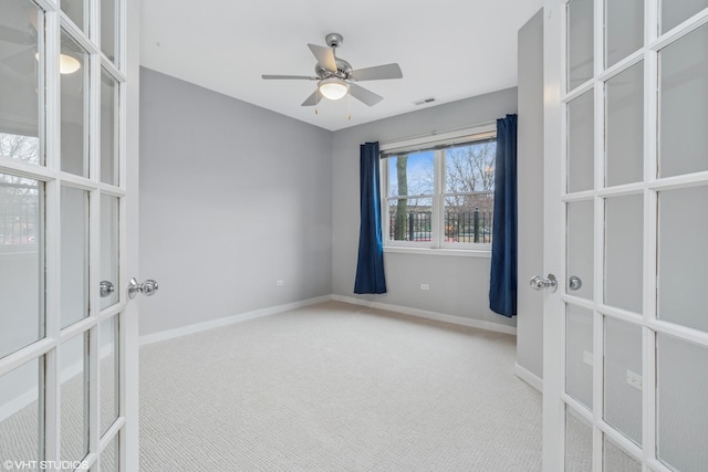 carpeted empty room featuring ceiling fan, french doors, visible vents, and baseboards