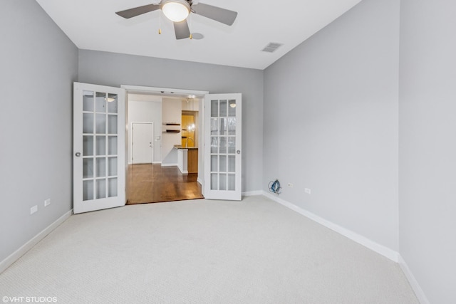 carpeted empty room with french doors, visible vents, ceiling fan, and baseboards