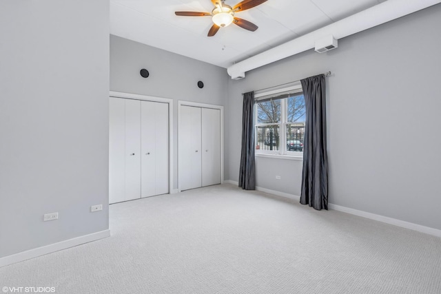 unfurnished bedroom with carpet, baseboards, and two closets