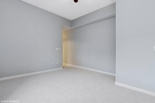 carpeted spare room featuring ceiling fan and baseboards