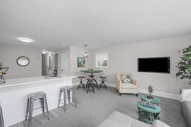 interior space with baseboards, a breakfast bar area, decorative light fixtures, and light colored carpet