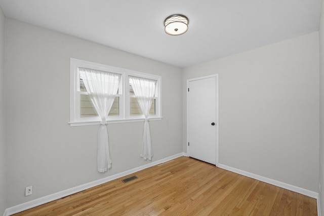 empty room featuring light wood-style flooring, visible vents, and baseboards