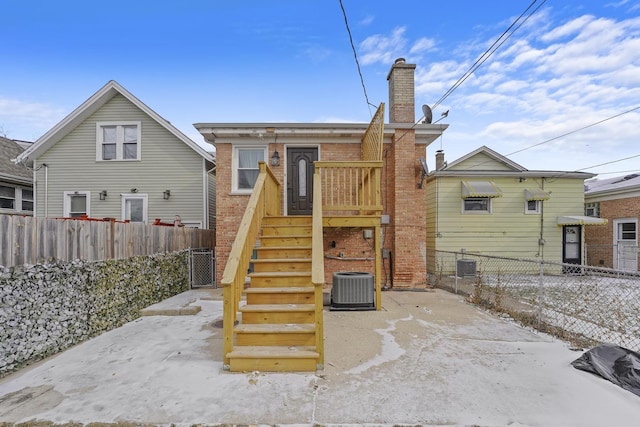 back of house featuring brick siding, a chimney, fence private yard, and cooling unit