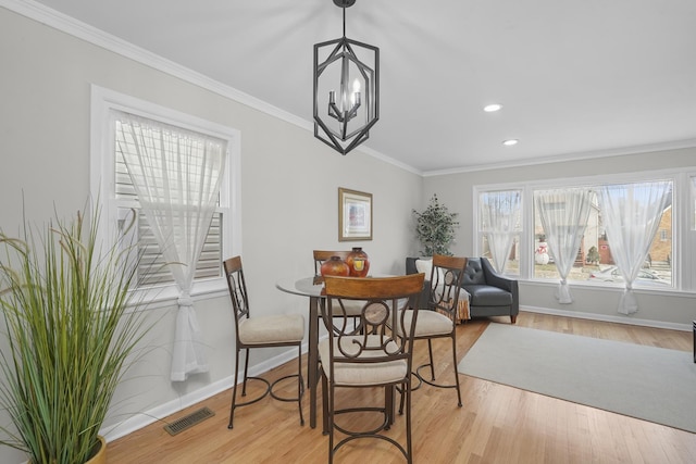 dining space with baseboards, wood finished floors, visible vents, and crown molding