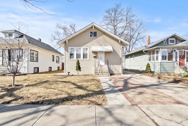 bungalow-style home featuring concrete driveway and entry steps