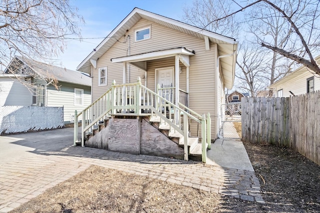 shotgun-style home featuring decorative driveway, a gate, and fence