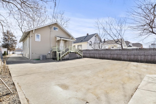 rear view of property featuring an outbuilding, cooling unit, and fence