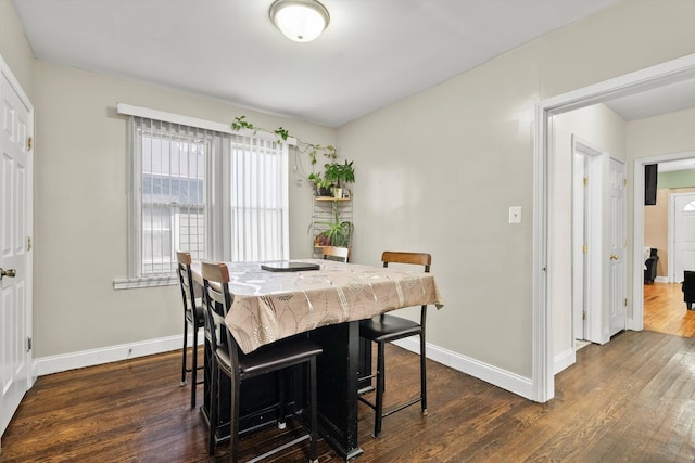 dining space with baseboards and dark wood-type flooring