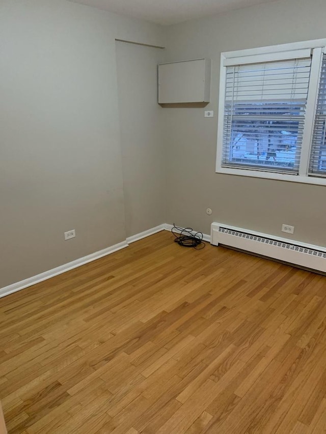 unfurnished room with light wood finished floors, baseboards, and baseboard heating