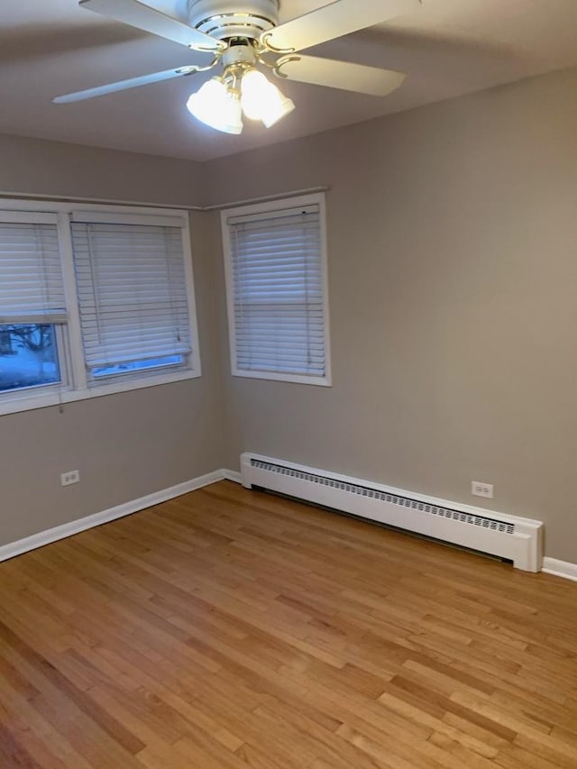 spare room featuring light wood-style floors, a baseboard radiator, baseboards, and a ceiling fan